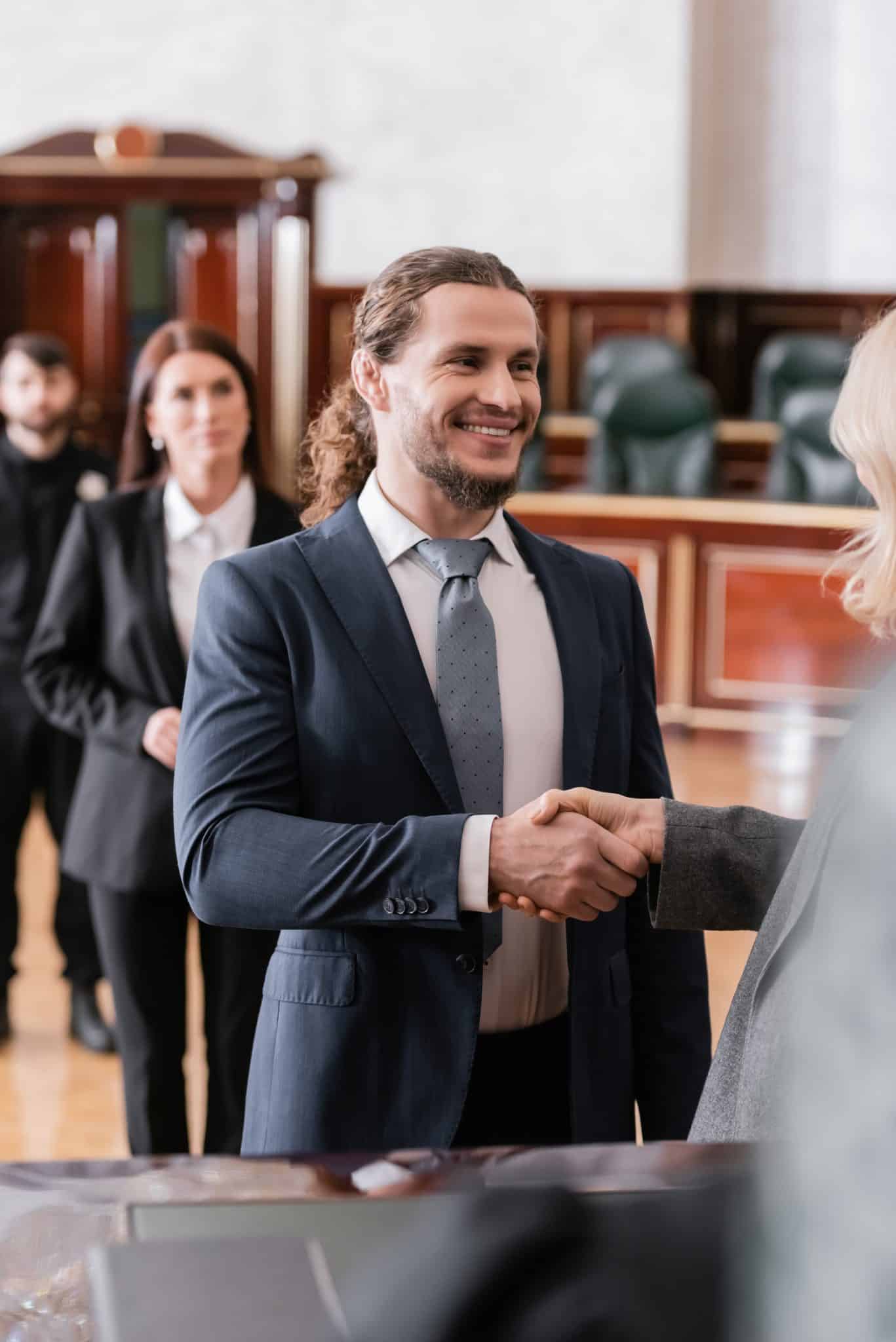 lawyer shaking hands with someone off-screen in a courtroom